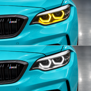 Türkisfarbener BMW M2 F87 mit gelbem und weißem Tagfahrlicht auf grauem Studioboden